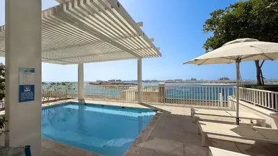 a swimming pool with an umbrella and a swimming poolvisor at Most Luxurious 2BR Apt Beach Access & Palm View in Dubai