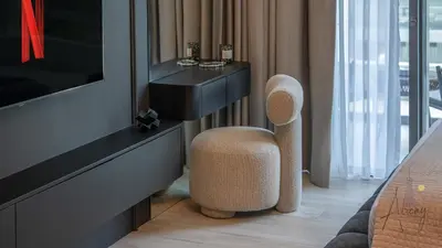 a room with a chair next to a tv at Grove Luxurious Stu Best community Art & Design in Dubai
