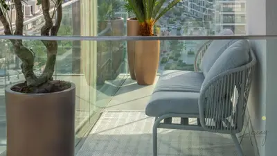 a balcony with a chair and a glass table at GroveLuxurious 1BR BEST communityArt & Design in Dubai