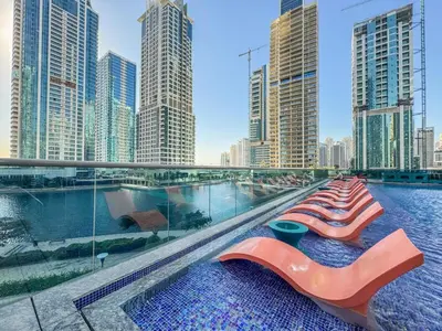 a pool with chaise lounges and a city skyline at Sky-High Luxury 1BR in 27th Floor MBL Residence in Dubai