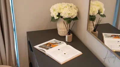a table with a vase of flowers and a book at Luxe Haven 1BR8min drive DubaiMall & BurjKhalifa in Dubai