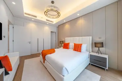 a bedroom with a large white bed with orange pillows at Luxury Comfort 1BRNear Dubai Mall & Burj Khalifa in Dubai