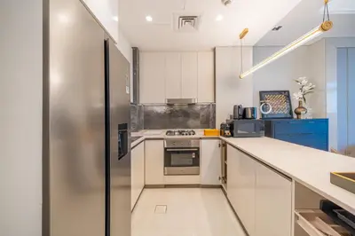 a kitchen with white cabinets and a stainless steel refrigerator at GEM 2BR Prime Location 8 Min to Burj Khalifa in Dubai