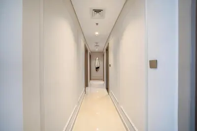 a hallway in a building with white walls and a long corridor at GEM 2BR Prime Location 8 Min to Burj Khalifa in Dubai