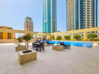 a patio with a pool and tables and chairs and buildings at Royal Oceanic Elegant 2BR with Marina View in Dubai