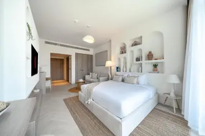 a white bedroom with a bed and a living room at Luxurious Design Boutique Studio Hideaway JVC in Dubai