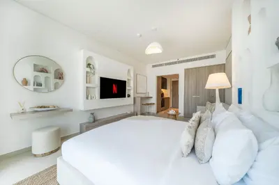 a white bedroom with a large bed and a tv at Luxurious Design Boutique Studio Hideaway JVC in Dubai