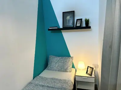 a small bedroom with a bed and a green wall at delightful Partition Room Barsha Heights Tecom in Dubai