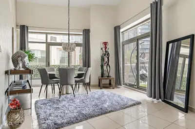 a dining room with a table and chairs and windows at VayK - Chic 1BR with Marina View in Park Island in Dubai