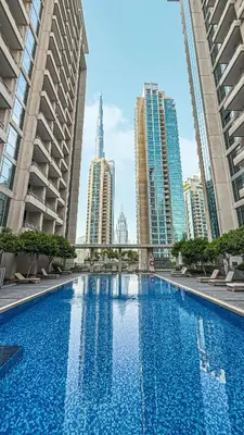 a large swimming pool in a city with tall buildings at Chic Studio Apartment, Pool and Balcony, Steps to Burj Khalifa in Dubai