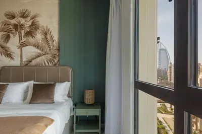a bedroom with a bed with a green wall and a window at Spacious 1BD, City View, Pool & Beach access in Dubai
