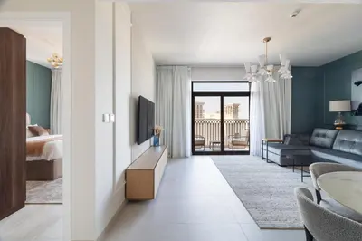 a living room with a bed and a living room with a couch at Spacious 1BD, City View, Pool & Beach access in Dubai