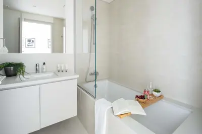a white bathroom with a tub and a sink at Frank Porter - Creek Palace in Dubai