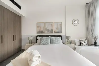 a white bedroom with a large white bed with pillows at Dubai Arjan Studio - Near Miracle Garden, Hills Mall & Attractions in Dubai