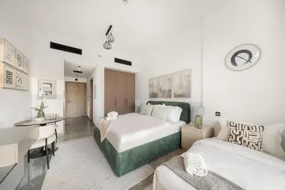 a hotel room with two beds and a desk at Dubai Arjan Studio - Near Miracle Garden, Hills Mall & Attractions in Dubai