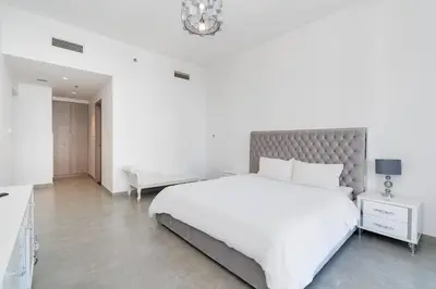 a white bedroom with a large bed and a chandelier at Elegant Living in the Heart of Dubai Marina in Dubai