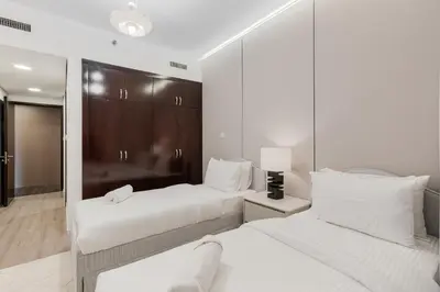 two beds in a hotel room with white sheets at Marina Tower Residences by Baytna in Dubai