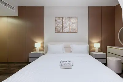 a bedroom with a large white bed with two lamps at Marina Tower Residences by Baytna in Dubai