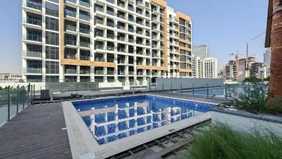 a building with a swimming pool in front of a building at AirDXB - Chic Studio Apartment in Meydan Sleeps 2 with Balcony in Dubai