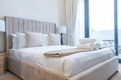 a bedroom with a large white bed with towels on it at AirDXB - Chic Studio Apartment in Meydan Sleeps 2 with Balcony in Dubai