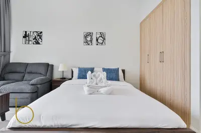 a bedroom with a large bed and a chair at Bookable - Alexis Tower, Studio Room with Balcony in Dubai