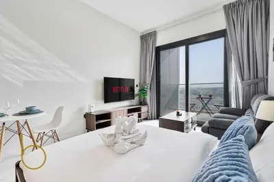 a bedroom with a white bed and a living room at Bookable - Alexis Tower, Studio Room with Balcony in Dubai