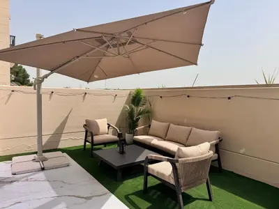 a patio with a couch and chairs and an umbrella at 3BR Luxury Townhouse with Garden in Dubai