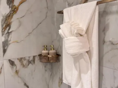 a bathroom with white towels hanging on a wall at 3BR Luxury Townhouse with Garden in Dubai
