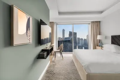 a hotel room with a bed and a desk and a window at Luxury in Dubai Marina Dining Pool Day & Beaches in Dubai