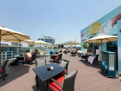 an outdoor patio with tables and chairs and umbrellas at GuestReady – Infinity Pool and Beach l Palm in Dubai