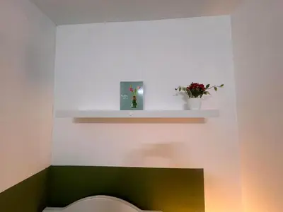 a bathroom with a toilet with a shelf and flowers at Tourist Partition Room Barsha Heights Tecom in Dubai