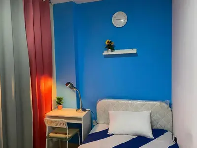 a blue room with a bed and a table with a clock at Divine Partition Room Barsha Heights Tecom in Dubai