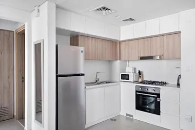 a kitchen with white cabinets and a white refrigerator at VayK - Large 1BR Near Hospital and Mall in Dubai