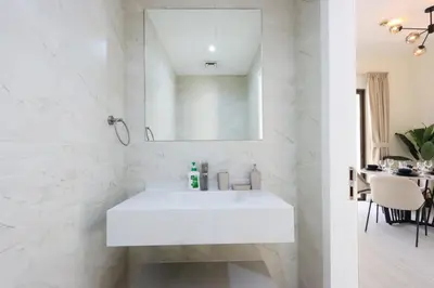 a white bathroom with a sink and a mirror at Upgraded 1BHK with Stunning Marina Views in Dubai