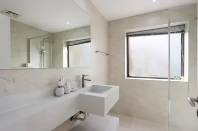 a white bathroom with a sink and a mirror at Upgraded 1BHK with Stunning Marina Views in Dubai