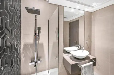 a bathroom with two sinks and a shower at Enjoy Modern Comforts with Views of Burj Al Aráb and Nearby Attractions in Dubai