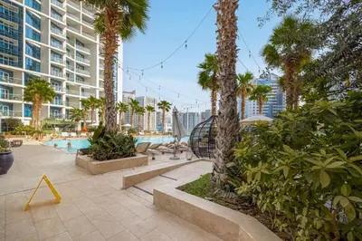 a swimming pool with palm trees and a building at Livin' Holidays - Studio - Close to downtown in Dubai