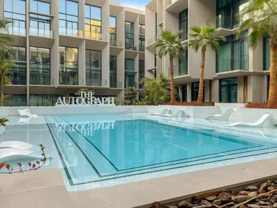 a swimming pool in front of a building with palm trees at Stylish studio Near Downtown Dubai with Pool & Gym Access in Dubai
