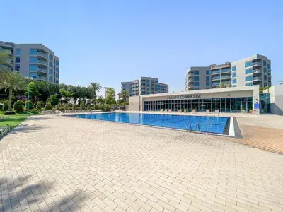 a swimming pool in front of a building with tall buildings at FIRST CLASS 1BR Elegant Comfort Awaits in Dubai