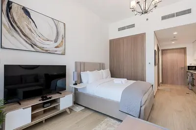 a bedroom with a bed and a flat screen tv at Studio Apartment near Al Quoz Pond Park in Dubai