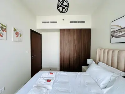 a bedroom with a white bed and a wooden door at Elite & Classy Furnished and Exquisite Living Room in Dubai