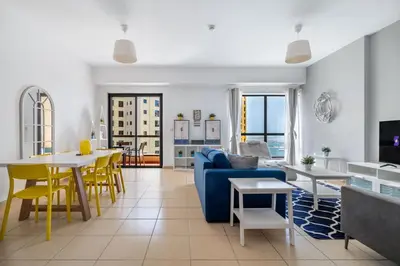 a living room with a blue couch and yellow chairs at Spacious 2BR Flat with Gym & Pool in JBR in Dubai