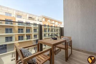 a balcony with a table and chairs and a building at Vogue JVC Chaimaa Avenue near Circle Mall, One Bedroom Apartment with Balcony and City View, Access to all Amenities in Dubai