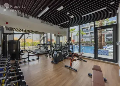 a gym with cardio equipment and a swimming pool at Vogue JVC Chaimaa Avenue near Circle Mall, One Bedroom Apartment with Balcony and City View, Access to all Amenities in Dubai