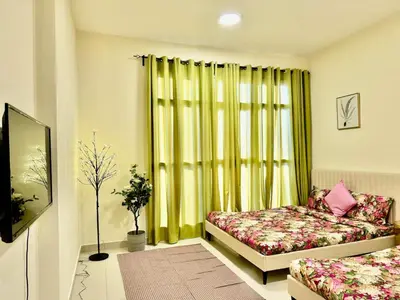 a room with two beds and a window with green curtains at Jaddaf NS Building in Dubai