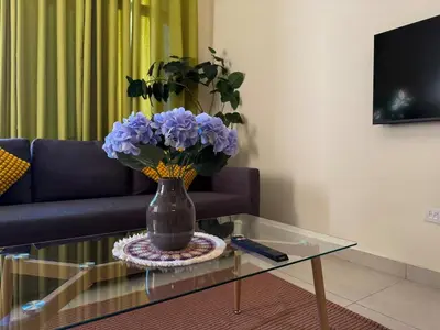 a vase with purple flowers on a glass table in a living room at Jaddaf NS Building in Dubai