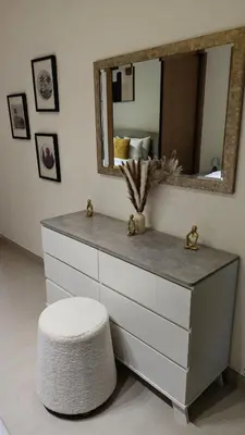 a white dresser with a mirror and a stool at Modern & Stylish 1BR, Pool & Gym in Dubai