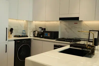 a white kitchen with a stove and a dishwasher at Modern & Stylish 1BR, Pool & Gym in Dubai