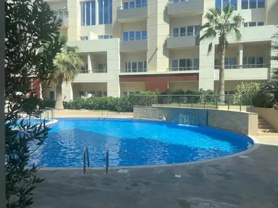 a large blue swimming pool in front of a building at Sandoval Gardens JVC in Dubai