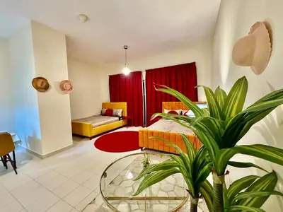 a bedroom with a bed and a table and a plant at Sandoval Gardens JVC in Dubai